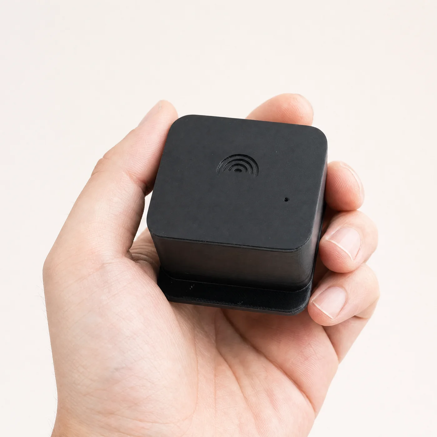 The GeoShake T1: a small matte black cube, held in a hand for scale